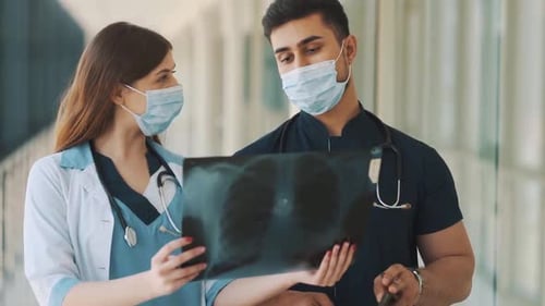 Medical Professionals Reviewing X-Ray in Hospital Corridor