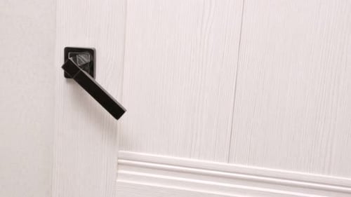 Child Opens the Door and Enters the Room Close Up Handle Door Twitches Someone is Trying to Enter in