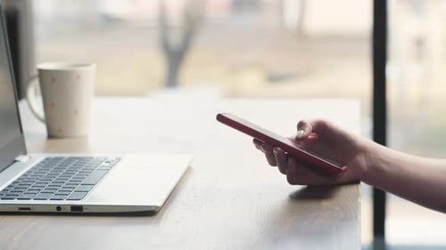 A Freelancer Girl Uses a Phone and a Laptop to Solve Work Tasks Cropped View of Woman Working From