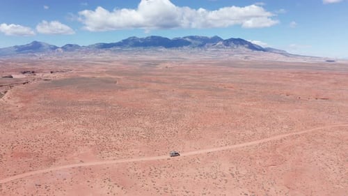Aerial, camper mini van on a road trip driving on sandstone desert road in Utah