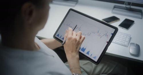 Female Financial Analyst Checking Exchange Market Charts on Tablet Computer Using Digital Pen