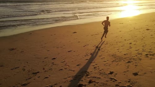 Aerial shot of a man jogging on the beach