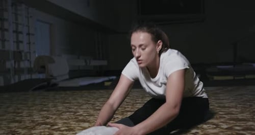 Young Woman Stretching on Carpet in Gym