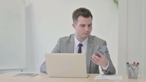 Young Adult Using Laptop and Smartphone in Office
