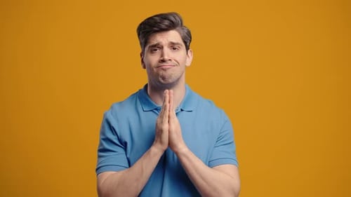 Man Clasping Hands Together in Prayer on Orange
