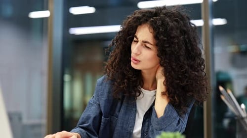 Tired Businesswoman Massaging Neck While Working on Laptop in Office