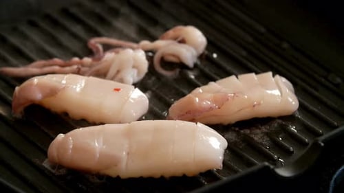 Close-up of Sizzling Calamari Being Cooked on a Ribbed Grill Pan