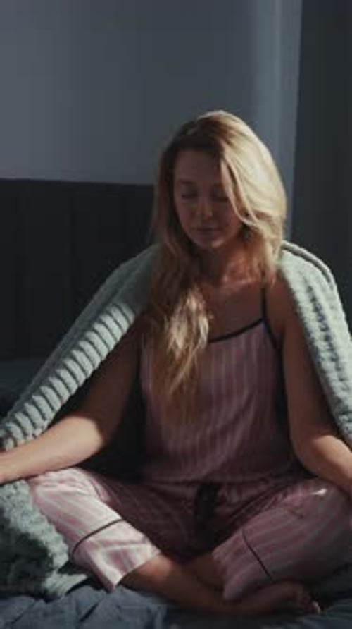 Woman Meditating on Bed Under Blanket