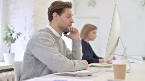 Happy Creative Man Talking on Smart Phone in Office