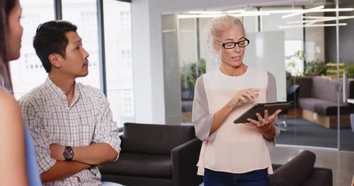 Discussing project details, colleagues collaborating in modern office with tablet