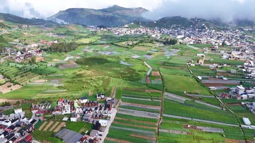Aerial drone view of a scenic mountain valley with lush green farmland, small houses