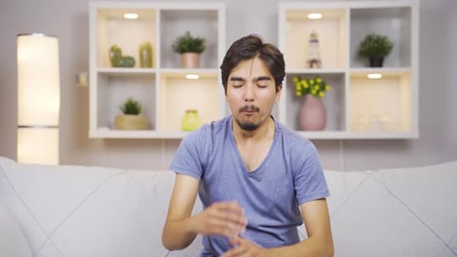 Young Adult Man Sitting on Couch Coughing