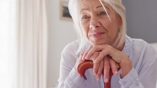 Senior Woman Resting with Walking Stick Indoors