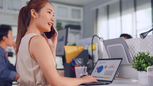 Asian happy businesswoman talking on smartphone and working in office.