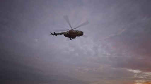 Military Helicopter Flying Across Cloudy Sunset Sky