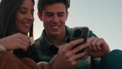 Happy Couple Laughs at Phone Outdoors