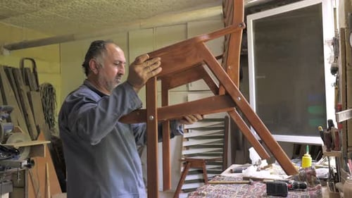 A Carpenter in His Workshop Assembles a Handmade Chair Screws a Bolt Secures It with a Hex Key