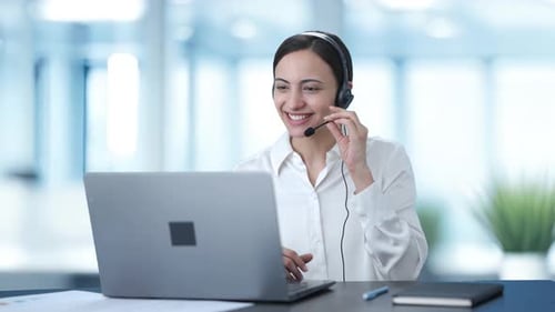 Happy Indian call center girl talking to customer through video call