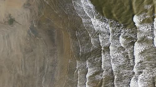 Waves crash rhythmically on sandy shores