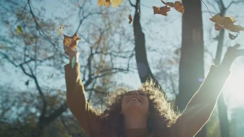 Caucasian ginger woman throw up autumn leaves and enjoying the weather. Shot with RED helium camera