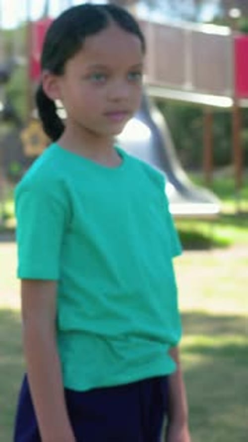 Vidéo verticale : fille changeant de caméra en chemise bleu sarcelle tenant un arbre posant sur un tapis violet dans un parc pour le yoga