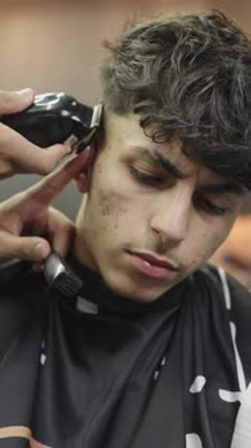 Young man getting haircut in barber shop