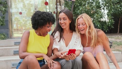 Three Friends Looking at Phone Together Outdoors