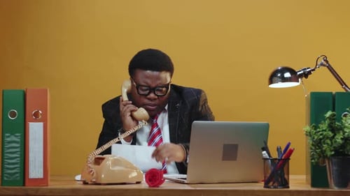 Man in Suit on Rotary Phone at Desk
