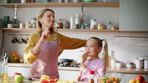 Familia bailando divirtiéndose cocinando la cena en una cocina luminosa sintiéndose alegre de cerca