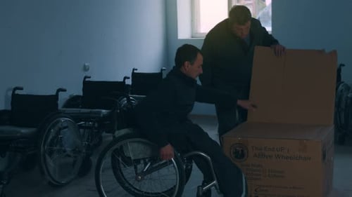 Side View of One American Male Workers in a Workshop at a Factory Making Wheelchairs Sitting at a