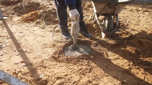 Appliquer des vibrations pour tasser correctement le béton humide Le travailleur utilise un vibrateur portatif pour le stabiliser