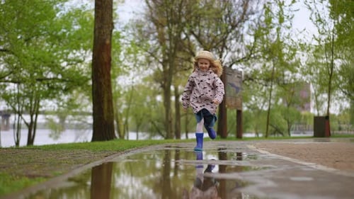 A Child Joyfully Plays in a Puddle at a Rainy Park Surrounded By Adventure and Excitement