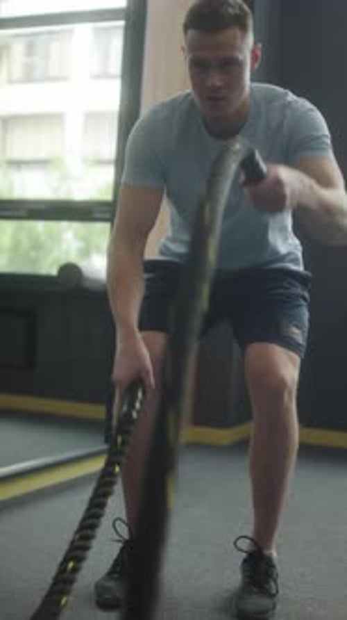 Man Working Out With Battle Ropes in Gym