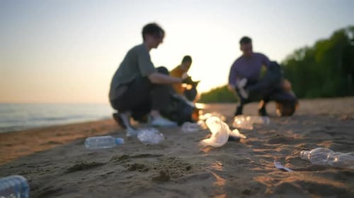 Freiwillige Leute sammeln Müll und sortieren Müll in Säcken an der Meeresküste bei Sonnenuntergang