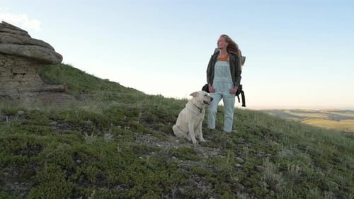 Woman and Dog Hike on Grassy Hillside