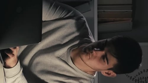 Young Adult Works on Laptop at Night Indoors