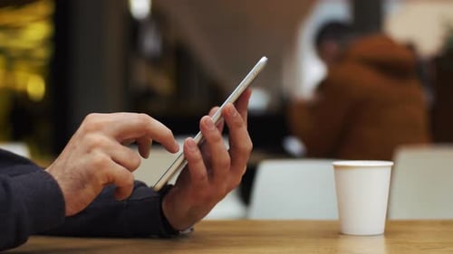 Man using tablet indoors with coffee on table