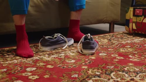 Person Puts on Striped Sock Indoors