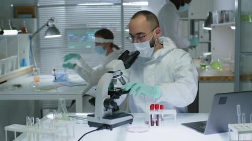 Männlicher Wissenschaftler schaut im Labor durchs Mikroskop