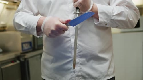 Chef in White Jacket Sharpening Knives at the Restaurant Cafe Kitchen Closeup of Man Hand Sharpen
