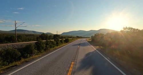 Driving a Car on a Road in Norway at dawn.