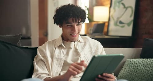 Young Man Relaxing on Couch Using Tablet