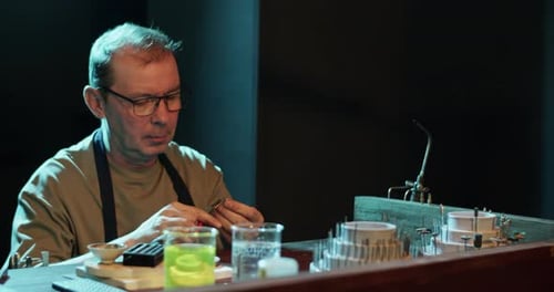 Concentrated Male Goldsmith Making Ring in Dark Workshop