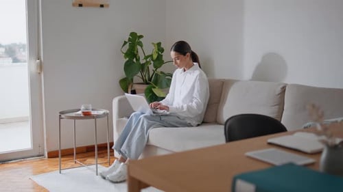 Woman Using Laptop on Couch at Home