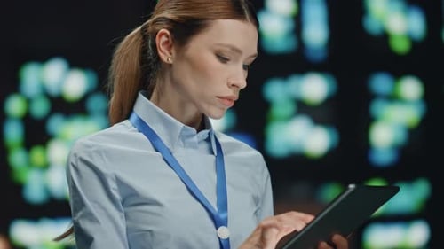 Woman Uses Tablet in Front of Tech Screen