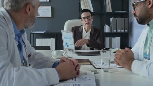 Female Clinic Director Leading Discussion with Medical Team at Office Meeting