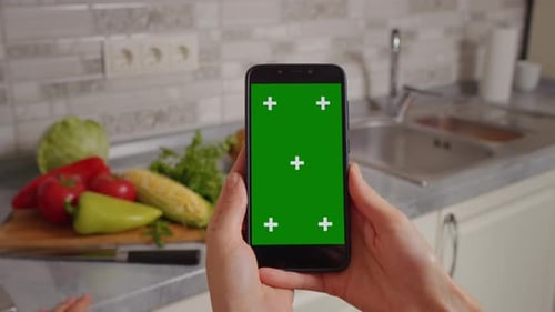 Womens hands with chroma key phone surfing for online recipes to cook for dinner with vegetables