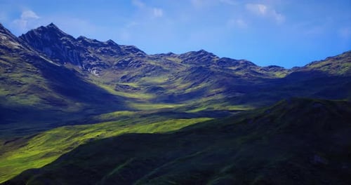Lush Green Valley Surrounded By Majestic Mountains Under Blue Sky