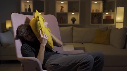 L'homme qui appuie les oreillers sur sa tête avec peur.