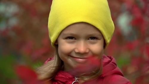 Girl Smiles in Autumn Park in Wind Child on Background of Red Foliage Outdoors